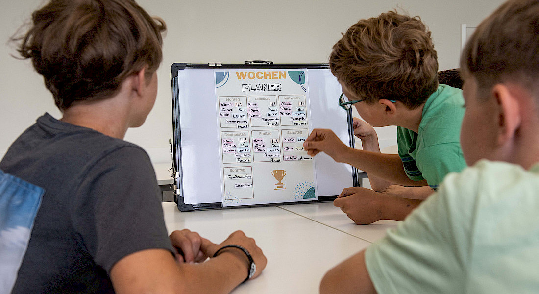 Drei Jugendliche gestalten und besprechen einen Wochenplan.