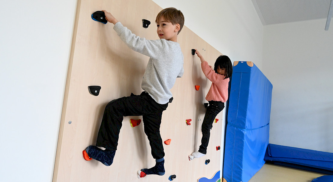 Zwei Kinder klettern an einer Indoor-Kletterwand.
