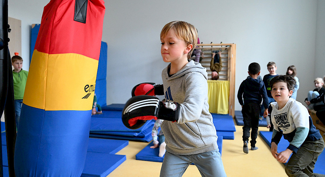 Ein Kind übt an einem Boxsack im Bewegungsraum.