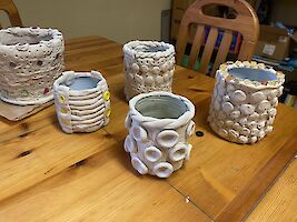 Mehrere weiße Vasen und Gefässe stehen auf einem Holztisch