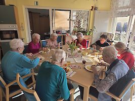 Gruppe sitzt um einen großen Tisch beim Mittagessen