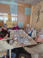 Personen sitzen in gemütlicher Rund um Kaffeetafel.