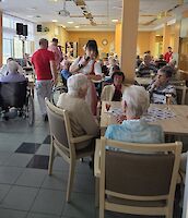 Musiker laufen durch Speisesaal der mit vielen Personen besetzt ist.