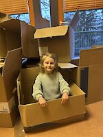 Kind sitzt in Umzugskiste