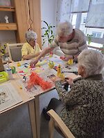 Mehrere Personen basteln an Tisch mit Zeitungen ausgelegt