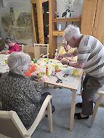 Mehrere Personen basteln an Tisch mit Zeitungen ausgelegt