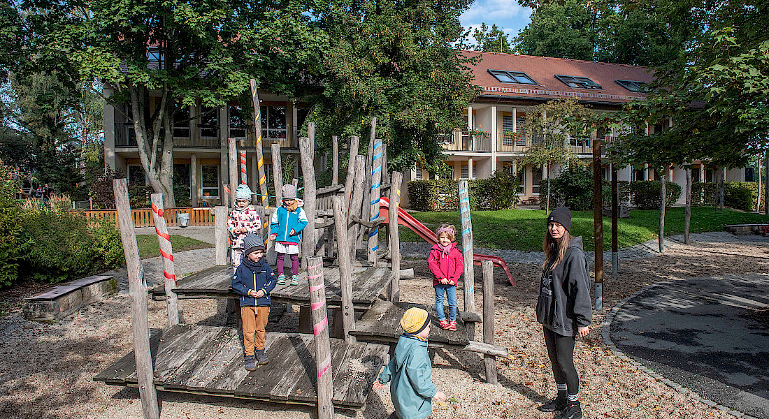 Kinder klettern auf einem Holzspielplatz im Garten einer Kita.