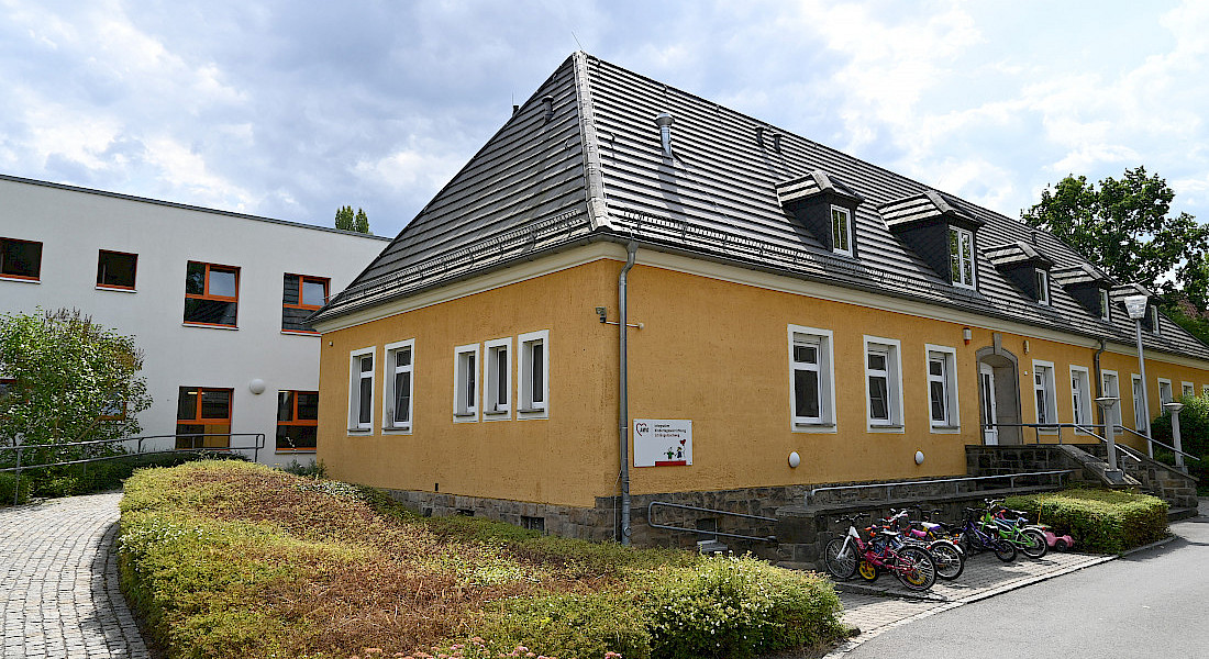 Kita-Gebäude mit gelber Fassade und Fahrrädern vor dem Haus.