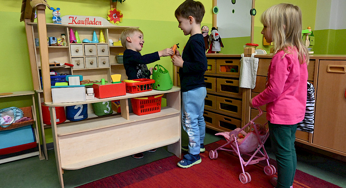 Kinder spielen gemeinsam mit einem Kaufladen.