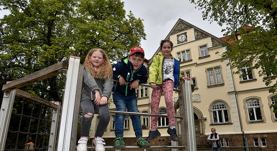 Kinder spielen draußen auf einem Klettergerüst.