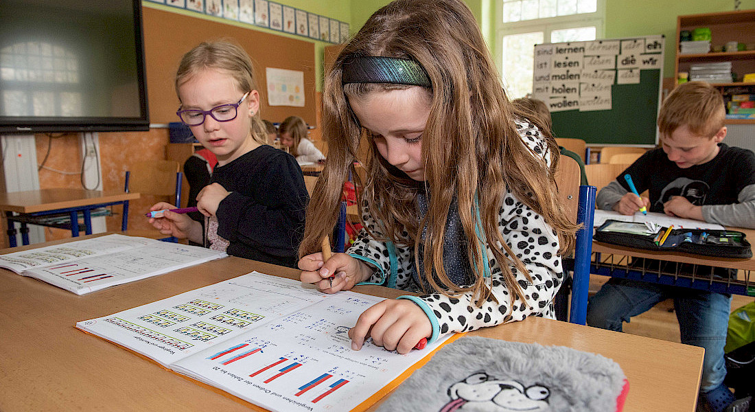 Zwei Kinder arbeiten konzentriert an Aufgabenheften.