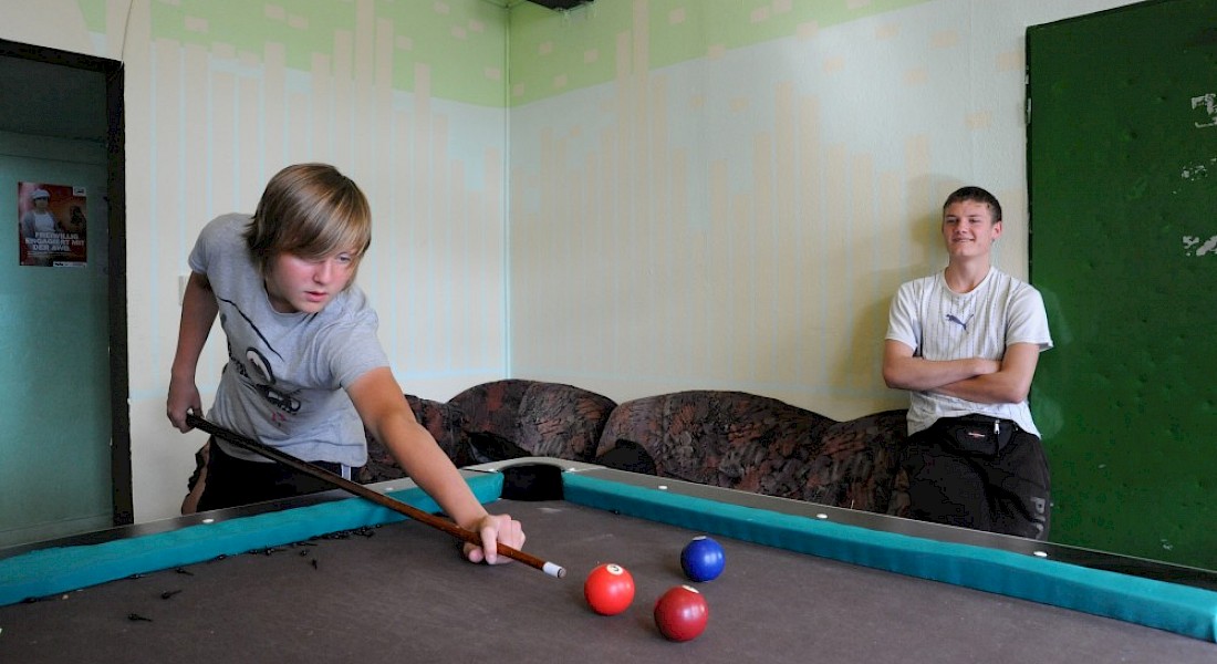 Zwei junge Leute spielen Billiard.