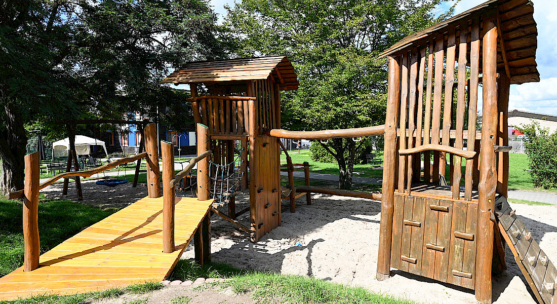 Ein großer Spielplatz mit Klettergerüst, Rutsche und Sandfläche.