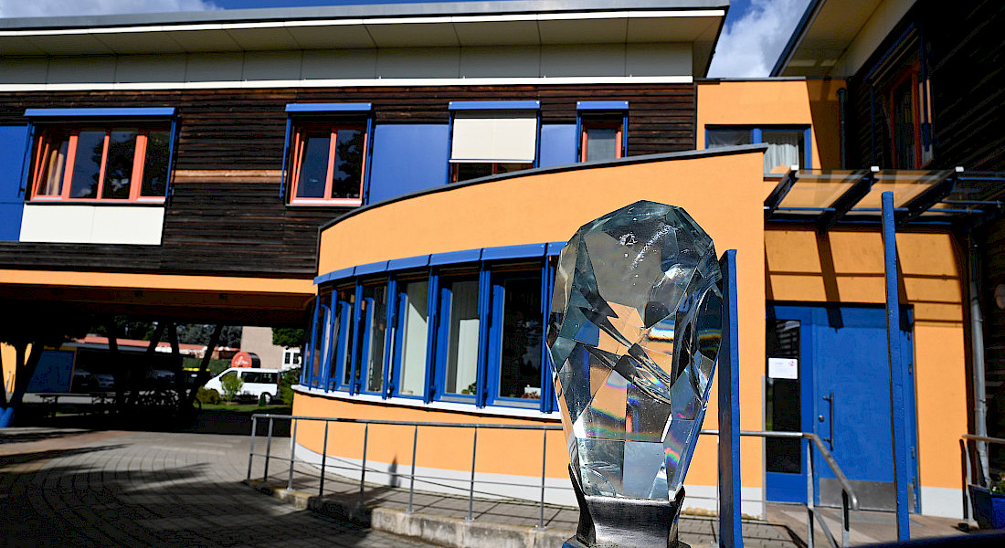 Außenansicht eines modernen Gebäudes mit farbiger Fassade und Skulptur.