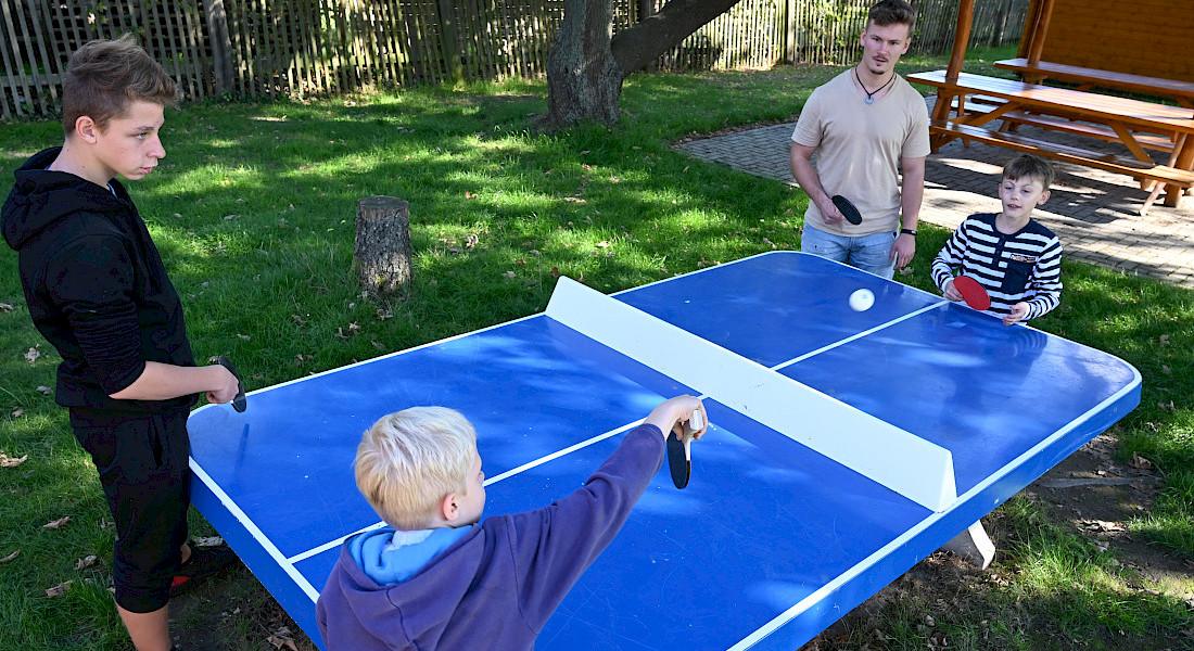 Kinder spielen draußen Tischtennis.
