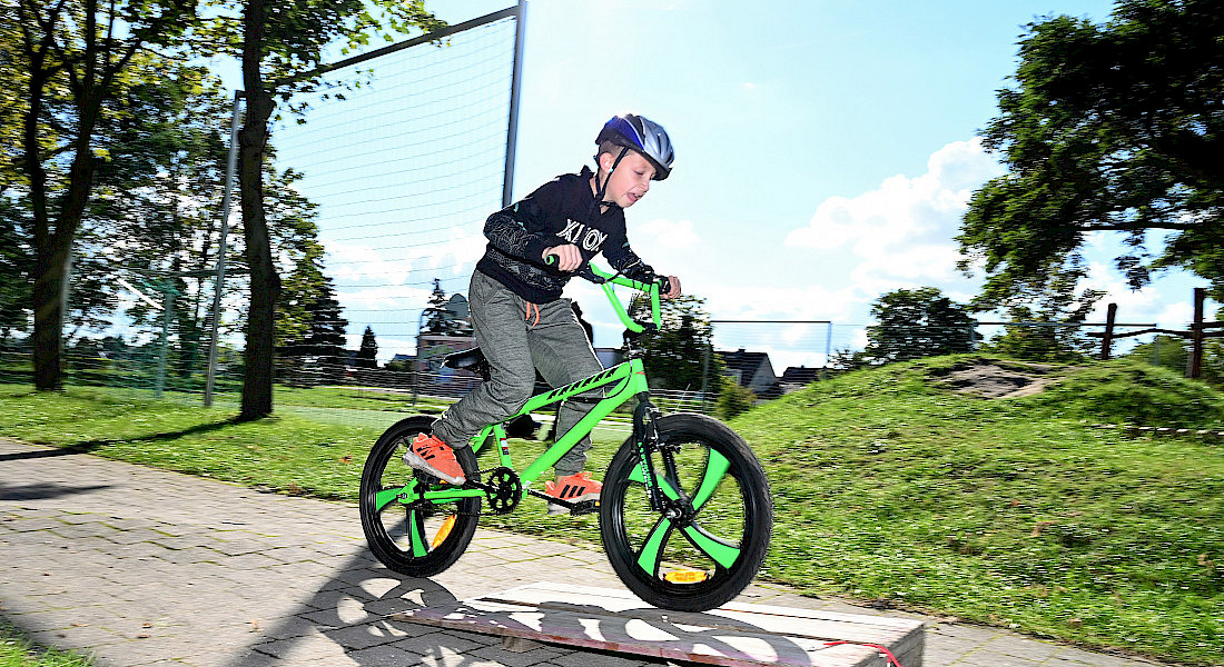 Ein Kind springt mit dem Fahrrad über eine kleine Rampe.