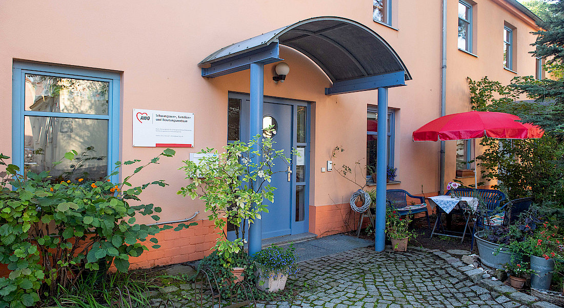Blick auf Gebäude mit freundlicher heller Fassade und vielen Grünpflanzen.
