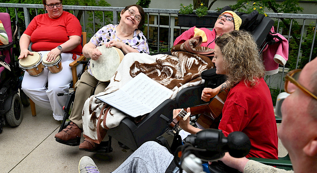 Eine Gruppe sitzt im Halbkreis und musiziert.