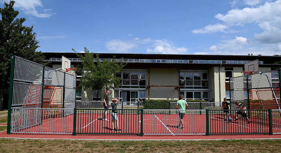 Außengelände mit Sportplatz mit Basketballkörben und Toren.