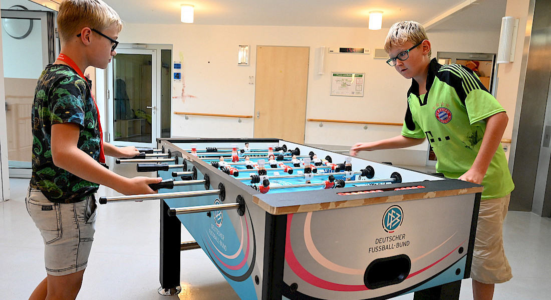 Zwei Jugendliche spielen Kicker.