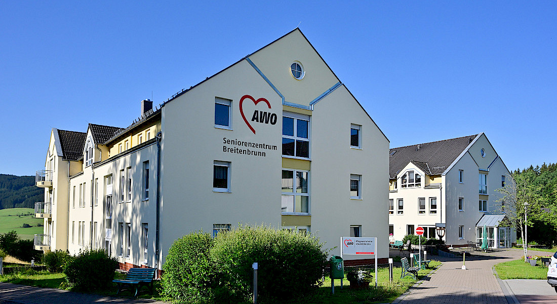 Außenansicht der dreistöckigen Einrichtung mit großem AWO-Logo an der Fassade und einer gepflegten Außenanlage in ländlicher Umgebung.